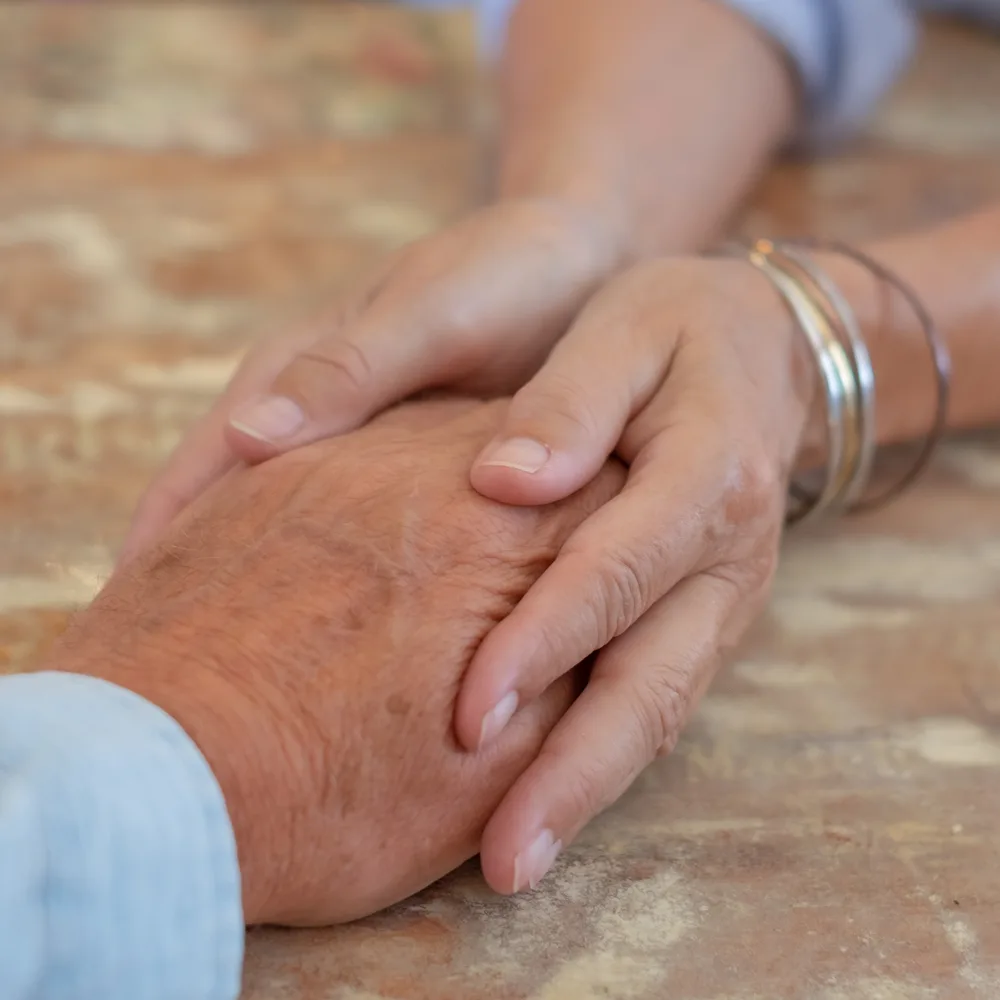 An older and a younger person's hands held in support