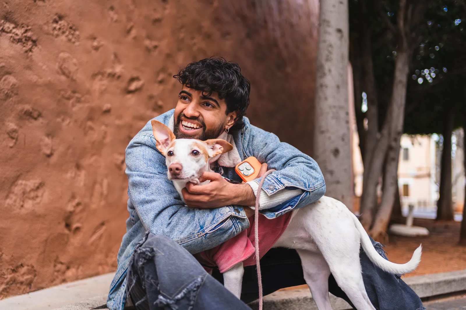 A young man hugging his dog in a park, both relaxed and happy