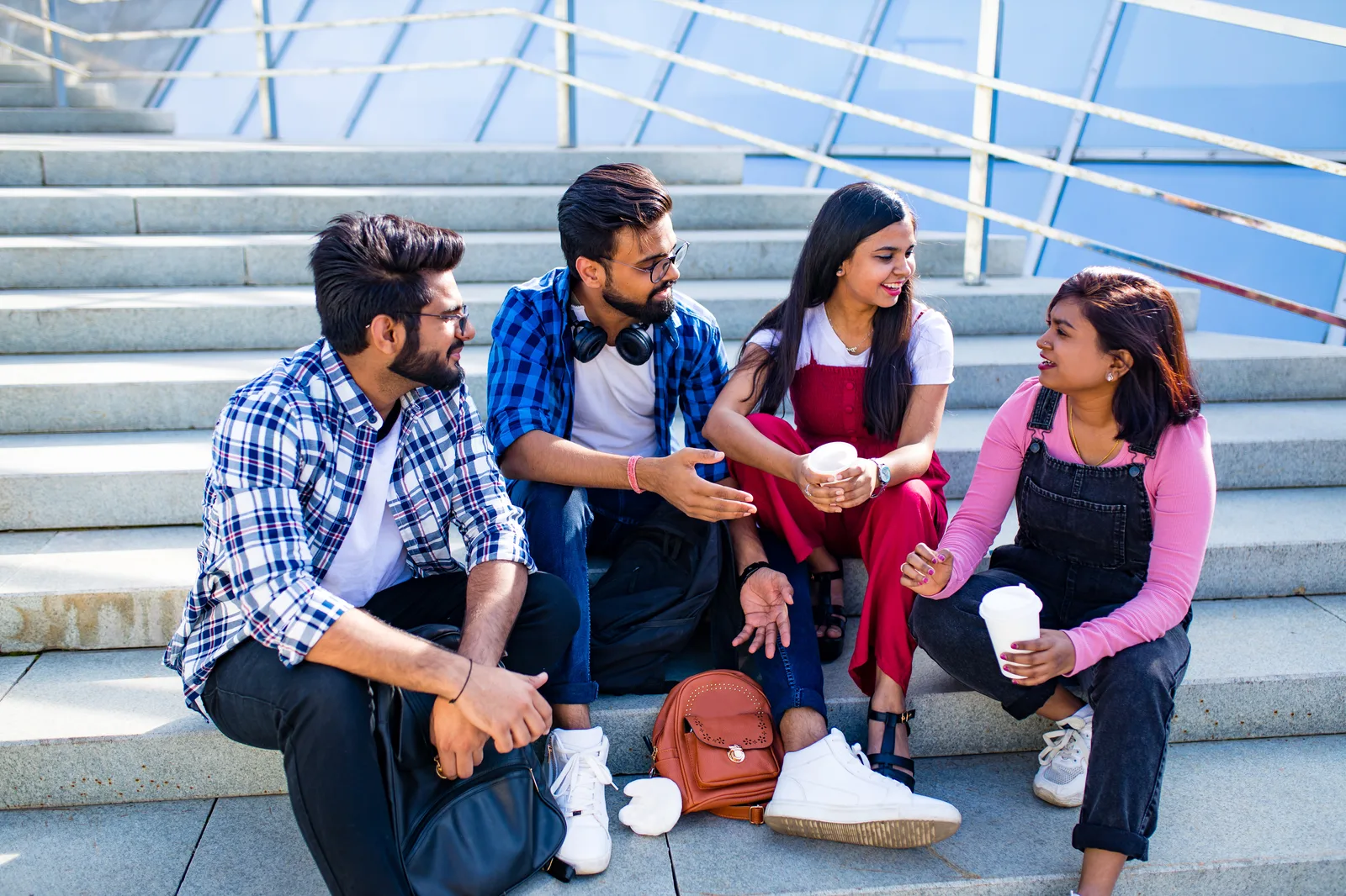 Young Indian friends chatting together on city steps